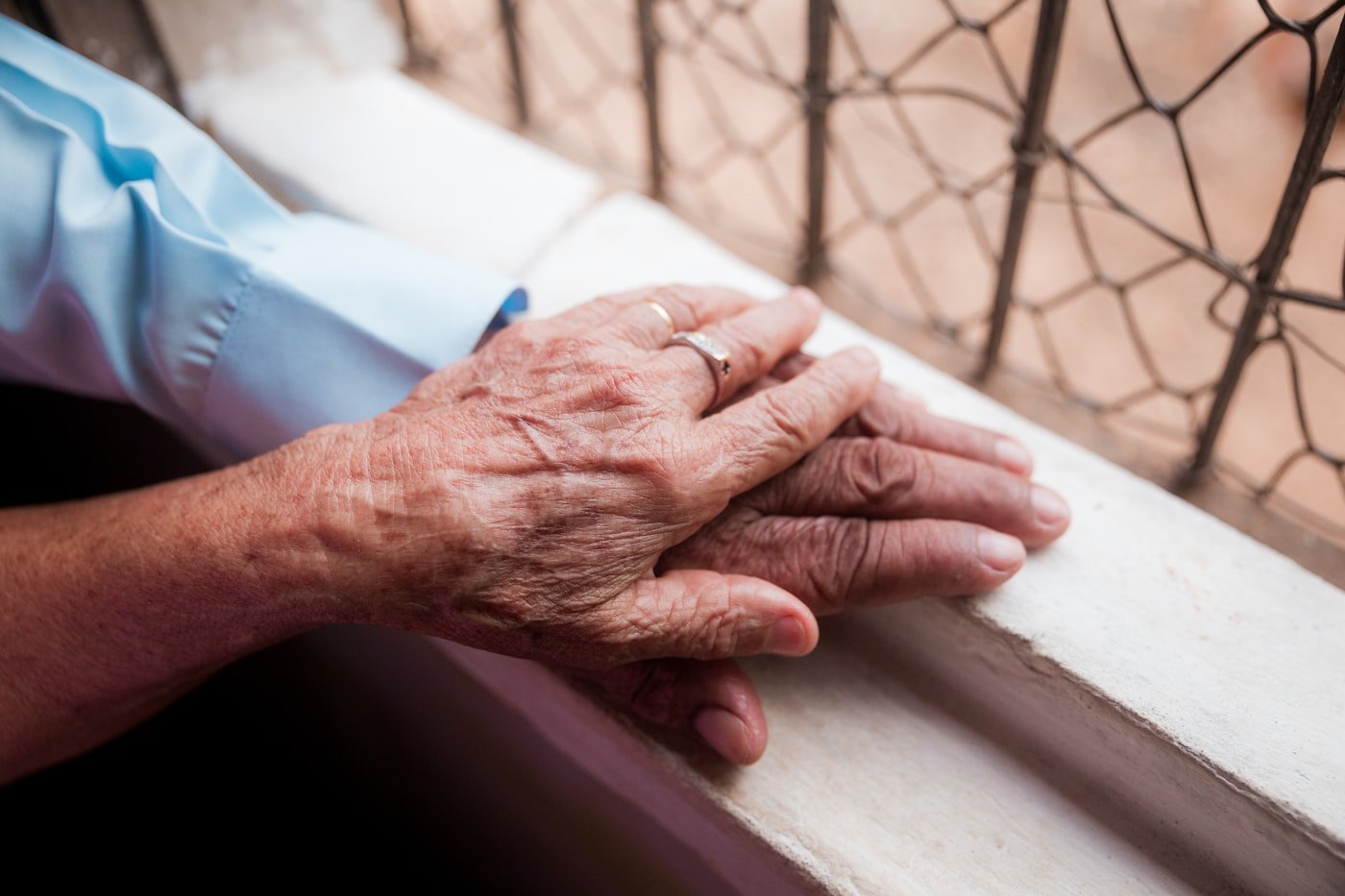 A younger hand gently holding an older hand during Alzheimers and dementia care at home