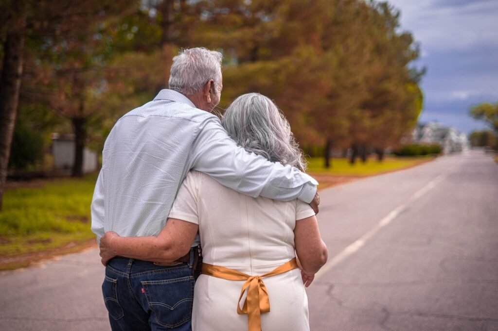 Senior couple walking arm in arm outdoors with caregiver mobility assistance