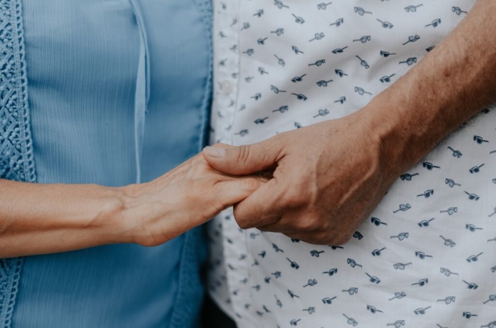 Caregiver holding the hand of a client recovering at home after surgery