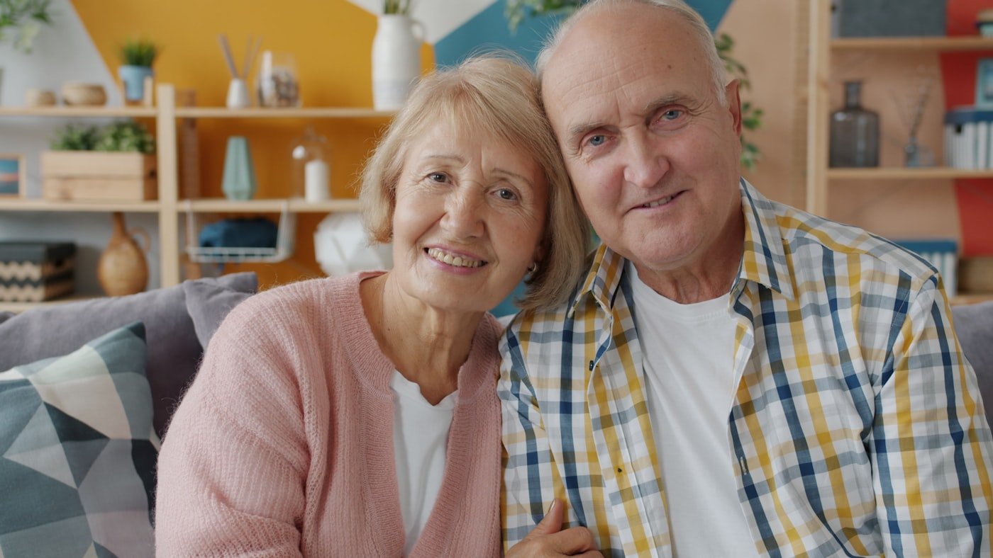 Elderly couple relaxing together at home while a respite caregiver supports the family